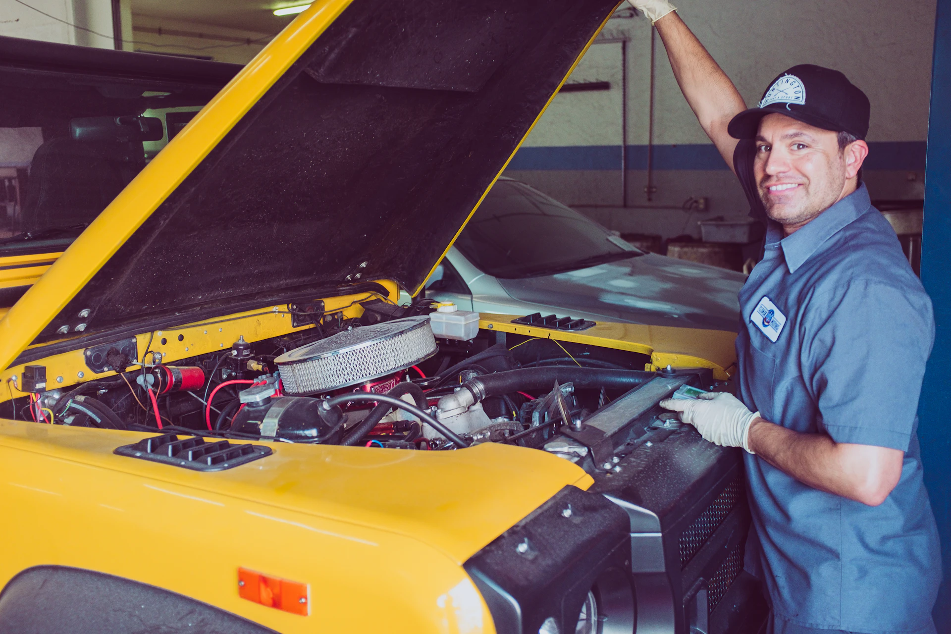Smiling mechanic beside an open engine bay at a Toronto auto repair shop