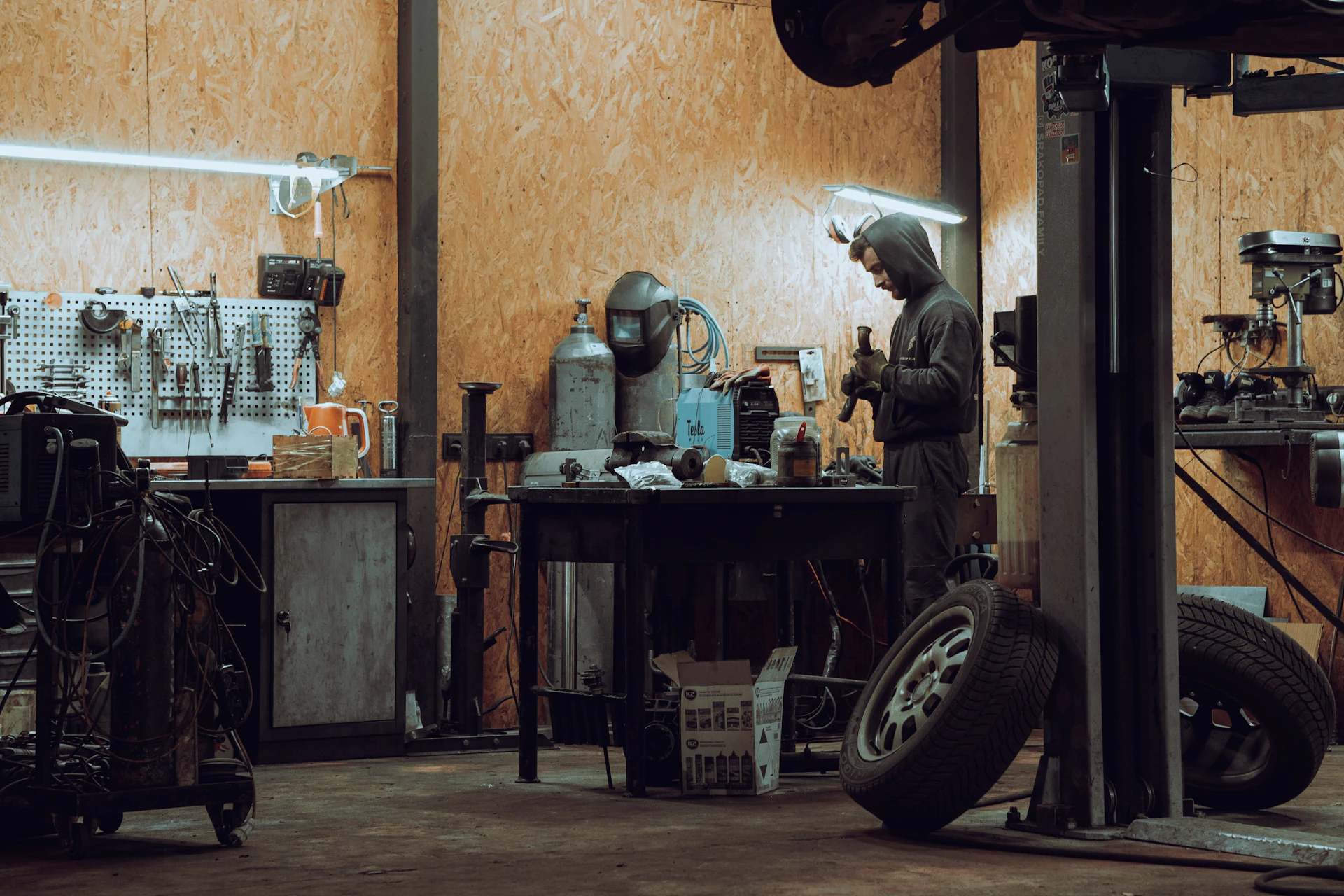 Mechanic at a workbench in a garage with a two-post lift in Toronto