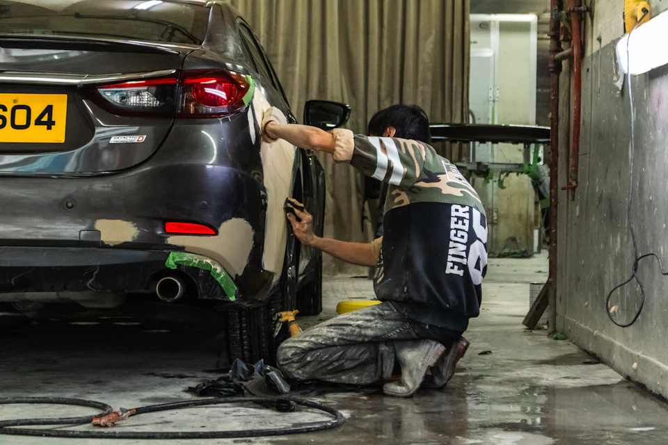 Auto body technician sanding a quarter panel and bumper for collision repair in Toronto
