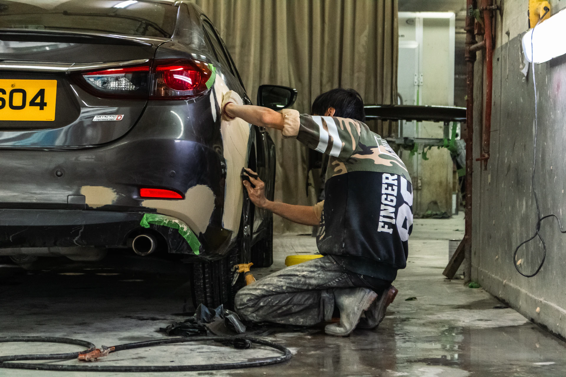 Auto body technician sanding a quarter panel and bumper for collision repair in Toronto