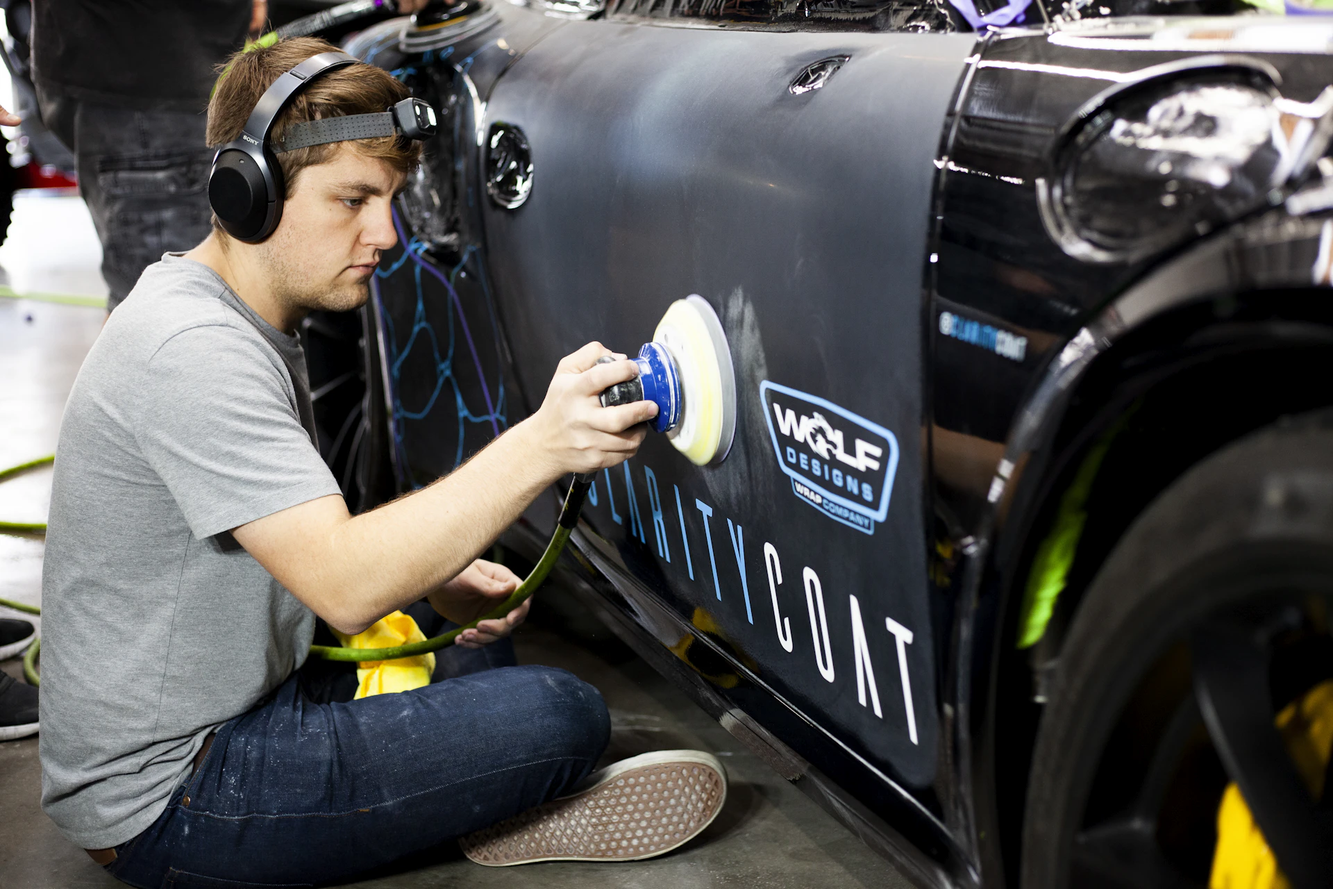 Auto body shop technician machine polishing a sports car after paint repair in Toronto