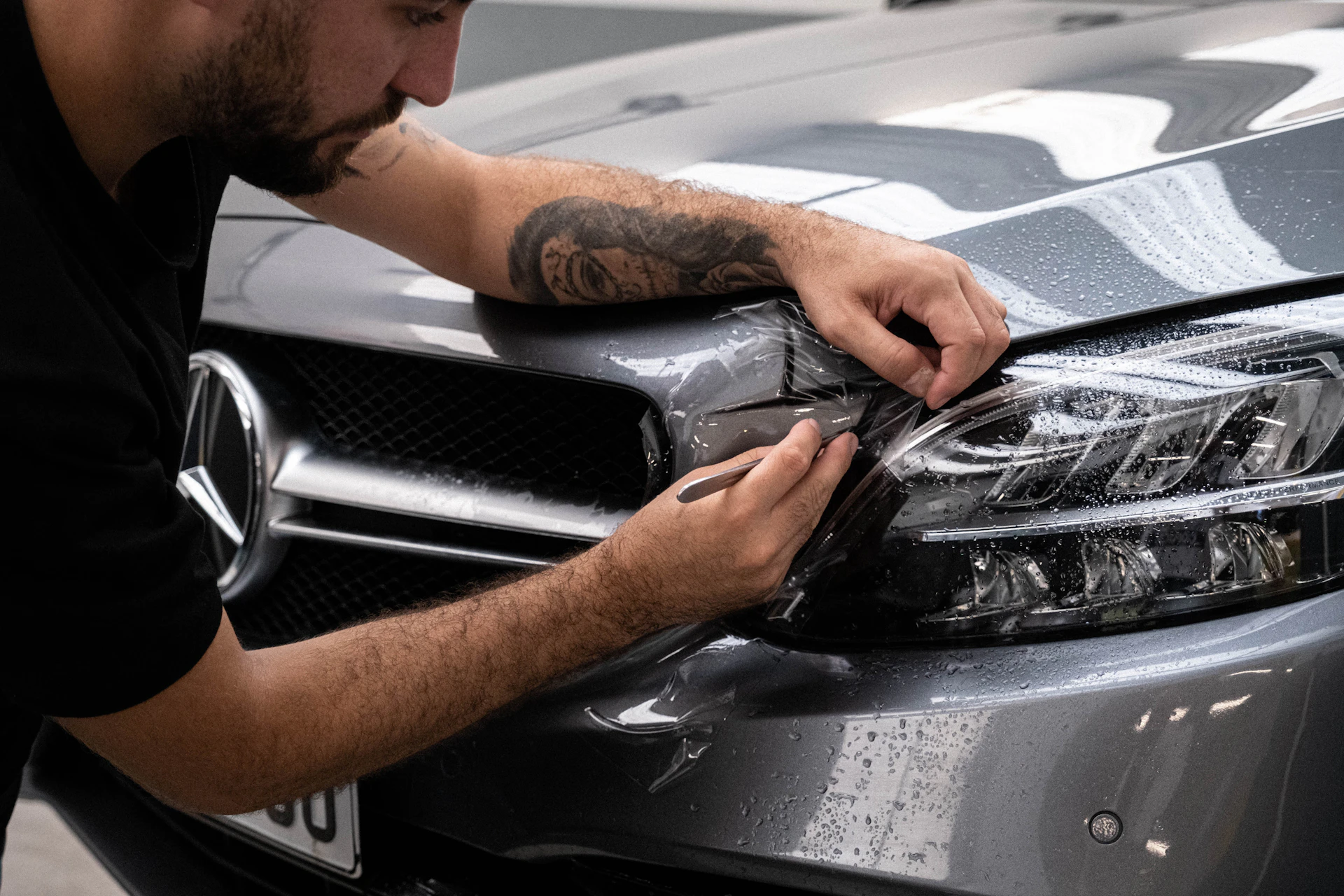 Technician finishing bodywork around a Mercedes-Benz headlight in a Toronto auto body shop