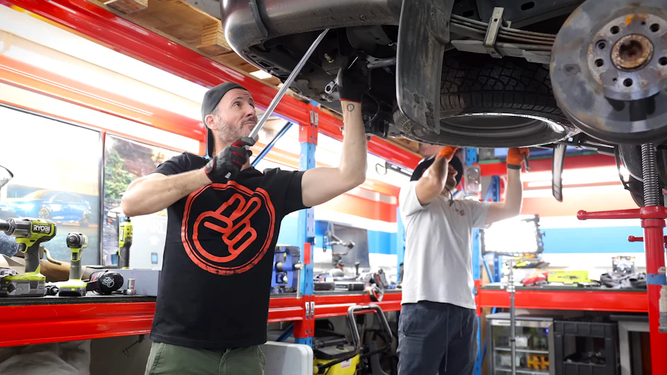 Technicians performing a structural inspection under a car on a lift in Toronto